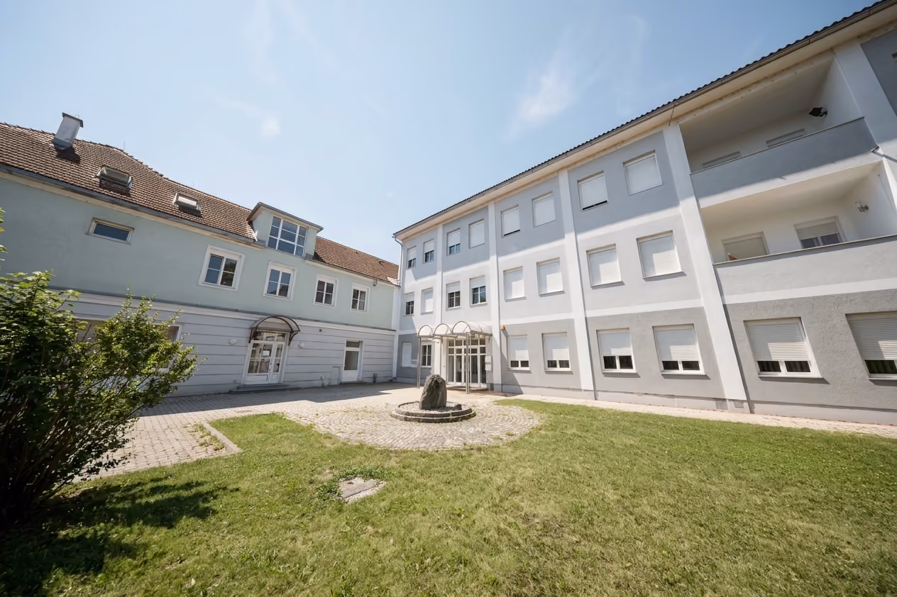 WK8: Innenhof mit Rasen und Brunnen zwischen Altbau und dreigeschossigem Wohngebäude