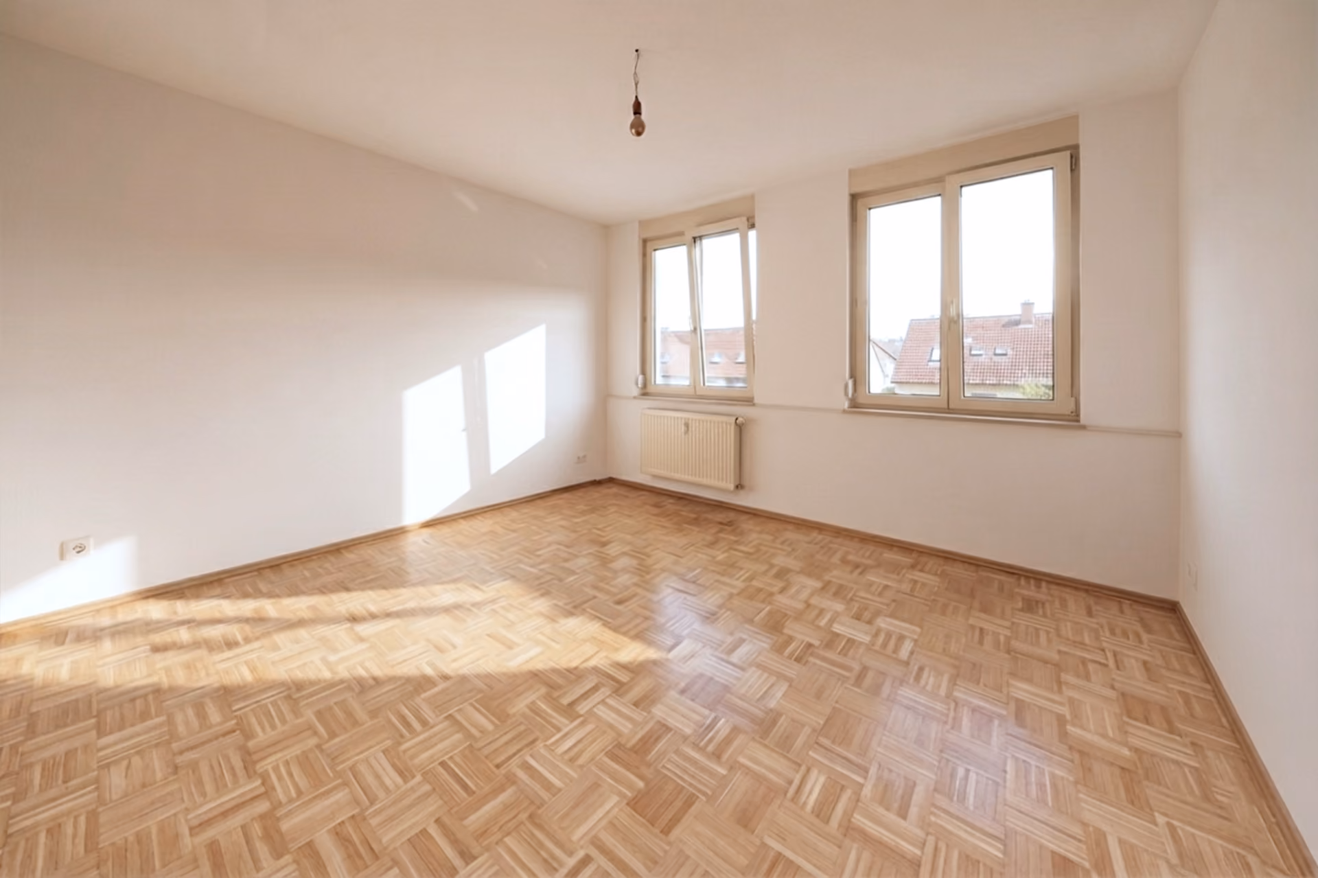 WK8: Leeres Zimmer mit Parkettboden und zwei Fenstern